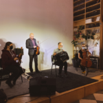 Zdjęcie przedstawia trzy osoby na scenie - muzyków - każdy z nich trzyma w ręku inny instrument muzyczny.